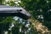 Hackspäne fliegen aus dem Auswurf des Holzhäckslers
